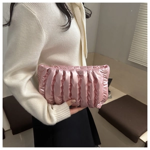 Detail der rosa gesteppten Clutch mit vertikalen Falten und goldenem Reißverschluss