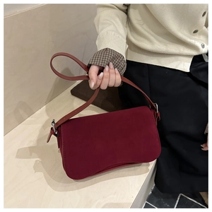 Detail view of burgundy suede handbag with flip cover and silver metal buckle strap