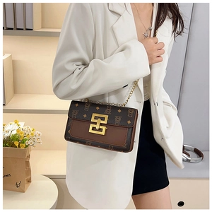 Détail du sac bandoulière avec motif d'ours et chaîne dorée sur blazer blanc