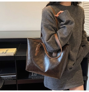 Detail of deep brown leather tote bag with gold lettering and adjustable straps