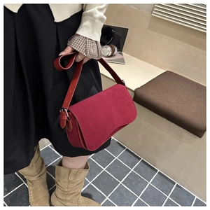 Close-up of red suede shoulder bag with magnetic flap and adjustable leather strap