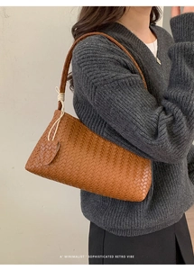 Détail d'un sac porté épaule en cuir tressé marron avec pendentif coeur assorti