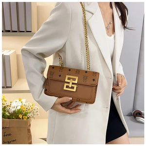 Détail d'un sac bandoulière marron avec imprimé ours, chaîne dorée et boucle métal