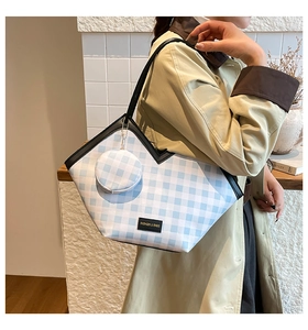 Detail of blue plaid tote bag with matching round coin purse and black strap accents