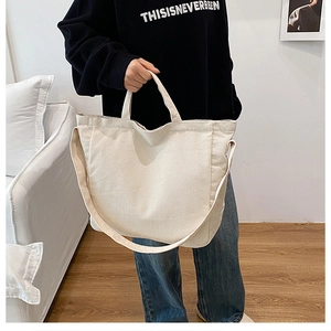 Dettaglio della borsa tote in velluto a coste bianco crema con trama e tracolla lunga su modella