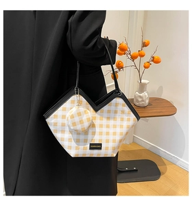 Detail of yellow checkerboard tote bag with black trim and matching mini coin purse charm