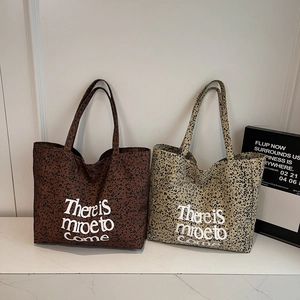 Leopard print canvas tote bags in brown and beige with artsy typography on marble table