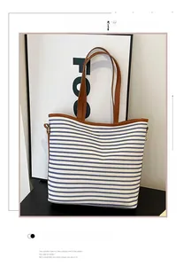 Detail view of striped canvas tote bag with brown leather handles and metal rings