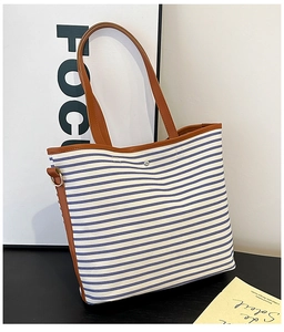 Detail view of the blue and white striped canvas tote bag with brown leather handles