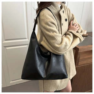 Detail of minimalist black pebbled leather tote bag with wide shoulder strap