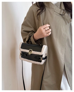 Close-up of contrast lamb wool patchwork and golden metal lock on a black crossbody bag