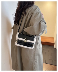 Detail of crossbody bag featuring black leather, white shearling trim and gold lock