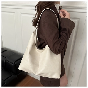 Close-up of creamy white large tote bag with textured faux leather and wide shoulder strap