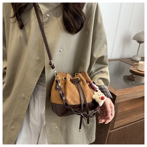 Detail of suede bucket bag featuring drawstring closure and cute white charm ornament