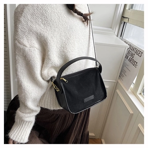 Détail du sac bandoulière noir montrant le daim mat et la texture du cuir lisse