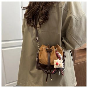 Brown suede bucket bag with drawstring closure and cute white plush pendant detail