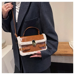 Close-up of brown faux leather crossbody bag with white shearling trim and gold clasp