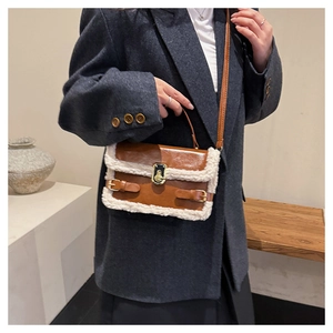 Close-up of brown leather handbag with white faux fur trim and gold twist lock detail