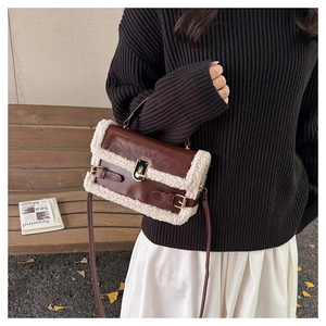 Detail of coffee leather baguette bag with white faux shearling trim and gold clasp