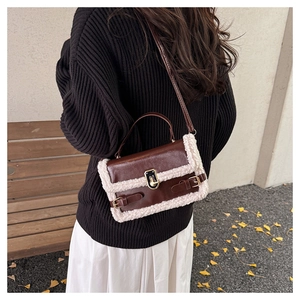 Detail of faux shearling trim on dark brown leather crossbody bag with metal clasp lock