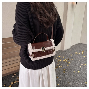 Detailed view of brown leather crossbody bag with white faux fur trim on ginkgo leaf ground