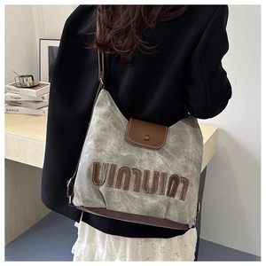 Detail der grauen Canvas-Hobo-Tasche mit braunem Lederpatchwork und Vintage-Dekor