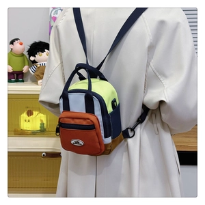 Detail of multi-color block nylon mini backpack with front zip pocket and sturdy handle