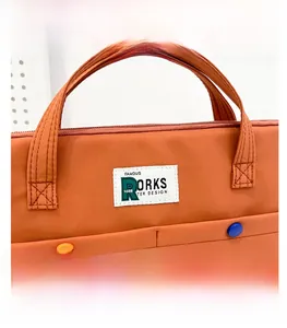 Détail d'une sacoche pour ordinateur en nylon marron avec étiquette tissée et poignées solides