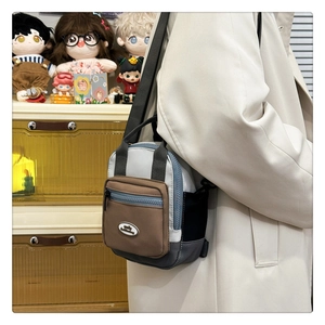 Close-up of a mini color-block nylon crossbody bag shown worn over a white coat