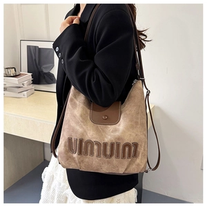 Detail of vintage brown textured leather hobo bag with adjustable strap and 3D lettering