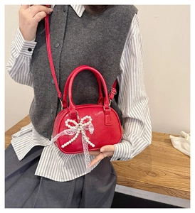 Red glossy bowling bag with pearl bow and lace detail worn as a crossbody by a model
