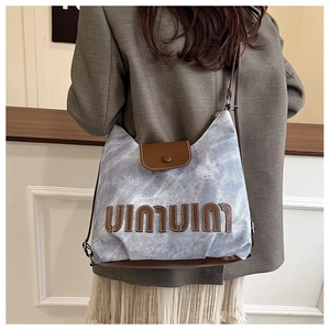 Detail of blue marbled canvas tote bag with brown leather accents and adjustable strap