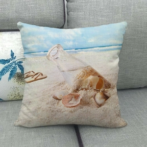 Detailed view of linen pillowcase with beach bottle print on a grey sofa