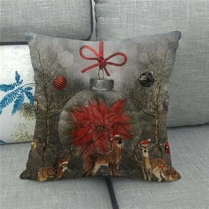 Detailansicht eines Kissenbezugs aus Leinen mit Elch und Weihnachtsblume auf Sofa