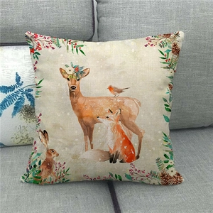 Detailansicht eines Leinen-Weihnachtskissens mit Aquarell-Rentier und Fuchs auf grauem Sofa