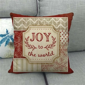 Detail of Joy to the World Christmas linen pillowcase on a grey sofa with snowflake patterns