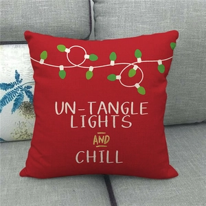 Detail of red Christmas linen pillowcase featuring festive light graphics and text on a sofa