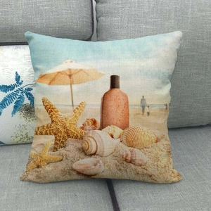 Linen beach cushion cover with starfish and seashell print on a soft grey fabric sofa