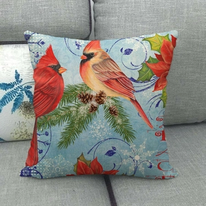 Christmas linen pillowcase with red cardinal birds and festive poinsettia on a sofa
