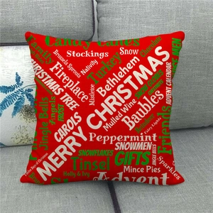 Detail of red Christmas linen pillowcase with festive typography on a gray sofa