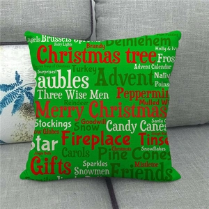 Detail of green linen Christmas pillow cover with festive typography on a grey sofa