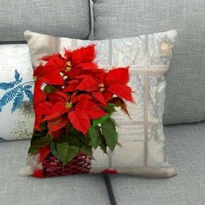 Detail of linen Christmas pillowcase with red poinsettia oil painting on grey sofa