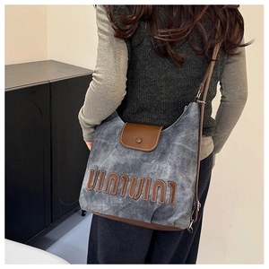Detail of vintage denim crossbody bag with leather patchwork and UIUI letter embroidery