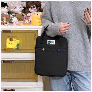 Détail d'une sacoche d'ordinateur noire en nylon avec boutons pression et poches de rangement
