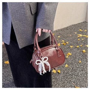 Dettaglio della borsa baguette in pelle marrone scuro con charm a fiocco di perle