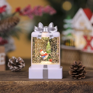Close-up of glowing Christmas gift box snow globe with skier and sparkling glitter