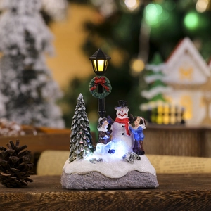 Close-up of glowing LED Christmas micro landscape with snowman and miniature kids