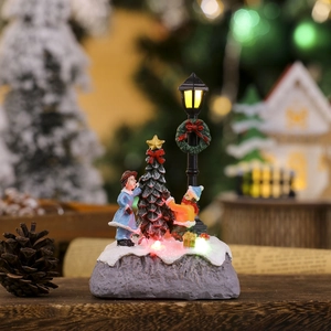 Close-up of glowing Christmas village resin figurine with snowman and lamppost detail