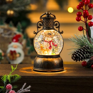 Macro view of vintage bronze Christmas snow globe lantern with warm LED light and snowmen