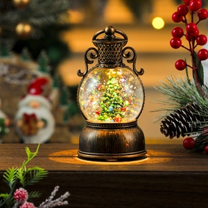 Macro view of Christmas snow globe lantern with internal tree and warm glowing base